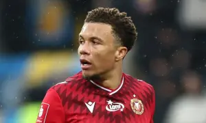 Piłkarz Rakowa Częstochowa w czerwonej koszulce z logo Lotto, gotowy do gry przeciwko Widzewowi Łódź.