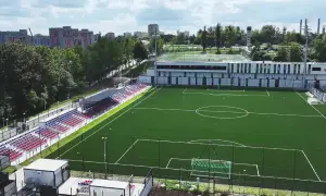 Nowy stadion Polonii Bytom z zieloną murawą, trybunami w kolorach czerwonym i niebieskim oraz nowoczesnym budynkiem klubowym.