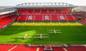 Piękny stadion w Anglii, Anfield, z czerwonymi trybunami i zieloną murawą, gotowy na kolejne emocjonujące mecze.