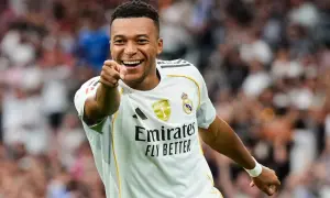 Uśmiechnięty piłkarz w białej koszulce Realu Madryt wskazuje palcem, jakby pytał: ile goli ma Mbappe?