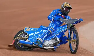 Bartosz Zmarzlik w niebieskim kevlarze z numerem 95, na motocyklu Orlen, ściga się na żużlu. Jego wzrost nie przeszkadza w dynamicznej jeździe.