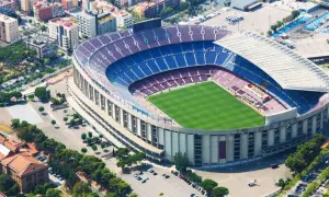 Widok z lotu ptaka na stadion Barcelony, z zieloną murawą i niebiesko-bordowymi trybunami.