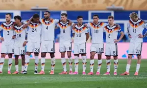 Drużyna Niemcy FC w białych strojach, z numerami na koszulkach, stoi na murawie.