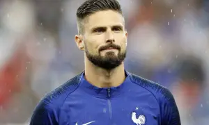 Olivier Giroud w deszczu, z charakterystycznymi fryzurami piłkarskimi i zarostem.