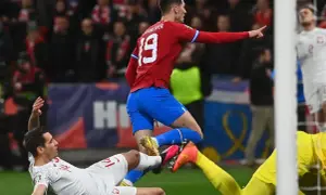 Piłkarz w czerwonej koszulce z numerem 19 wskazuje palcem, podczas gdy zawodnik w białej koszulce leży na ziemi. Emocje jak w polskiej Szwajcarii!