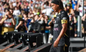 Ronaldinho w czarnej koszulce z żółtym opaską na ramieniu, z tłumem w tle.