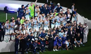 Piłkarze Argentyny świętują zwycięstwo, trzymając puchar. Wszyscy w biało-niebieskich strojach, z medalami na szyjach, tworzą najlepszą drużynę na świecie.