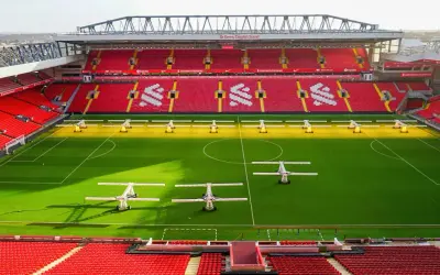 Piękny stadion w Anglii, Anfield, z czerwonymi trybunami i zieloną murawą, gotowy na kolejne emocjonujące mecze.