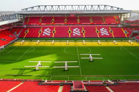 Piękny stadion w Anglii, Anfield, z czerwonymi trybunami i zieloną murawą, gotowy na kolejne emocjonujące mecze.