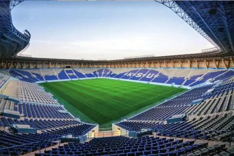 Puste trybuny stadionu Al Nassr czekają na kibiców. Zielona murawa lśni w słońcu, gotowa na emocjonujące mecze.