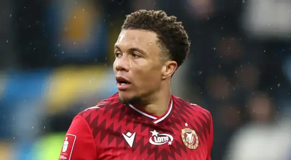 Piłkarz Rakowa Częstochowa w czerwonej koszulce z logo Lotto, gotowy do gry przeciwko Widzewowi Łódź.