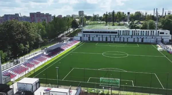 Nowy stadion Polonii Bytom z zieloną murawą, trybunami w kolorach czerwonym i niebieskim oraz nowoczesnym budynkiem klubowym.