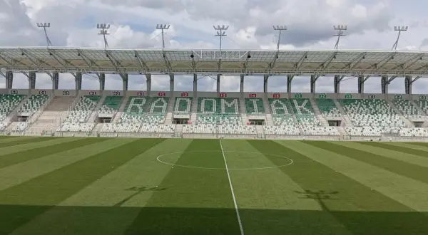 Puste trybuny stadionu RKS Radomiak Radom z napisem "RADOMIAK" ułożonym z zielonych i białych siedzeń.