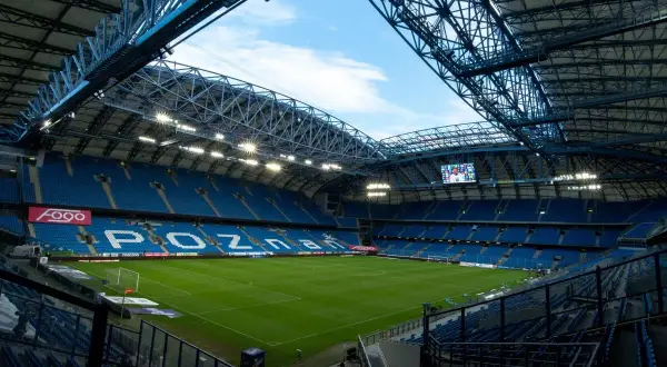 Pusta, błękitna trybuna stadionu Lecha Poznań, gotowa na przyjęcie kibiców. Pojemność stadionu robi wrażenie.