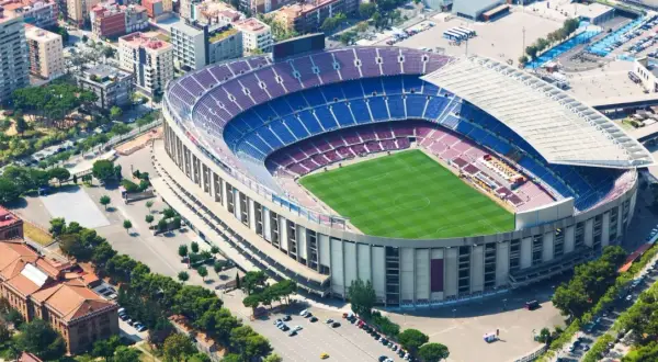 Widok z lotu ptaka na stadion Barcelony, z zieloną murawą i niebiesko-bordowymi trybunami.
