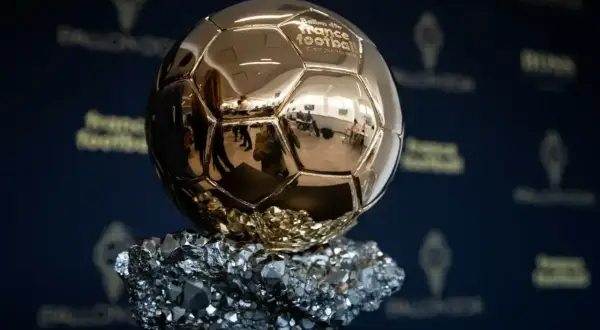 Złota Piłka, symbol triumfu na gali, lśni na tle logo France Football.