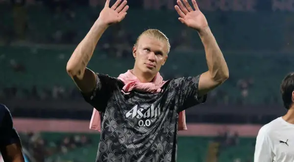 Erling Haaland z podniesionymi rękami, w koszulce z logo Asahi. Fani zastanawiają się nad jego datami dołączenia do drużyny.
