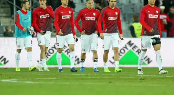 Młodzieżowa reprezentacja Polski w strojach meczowych na murawie.