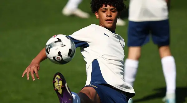 Młody piłkarz, niczym cr7 jr., trenuje na boisku, wykonując efektowne kopnięcie.