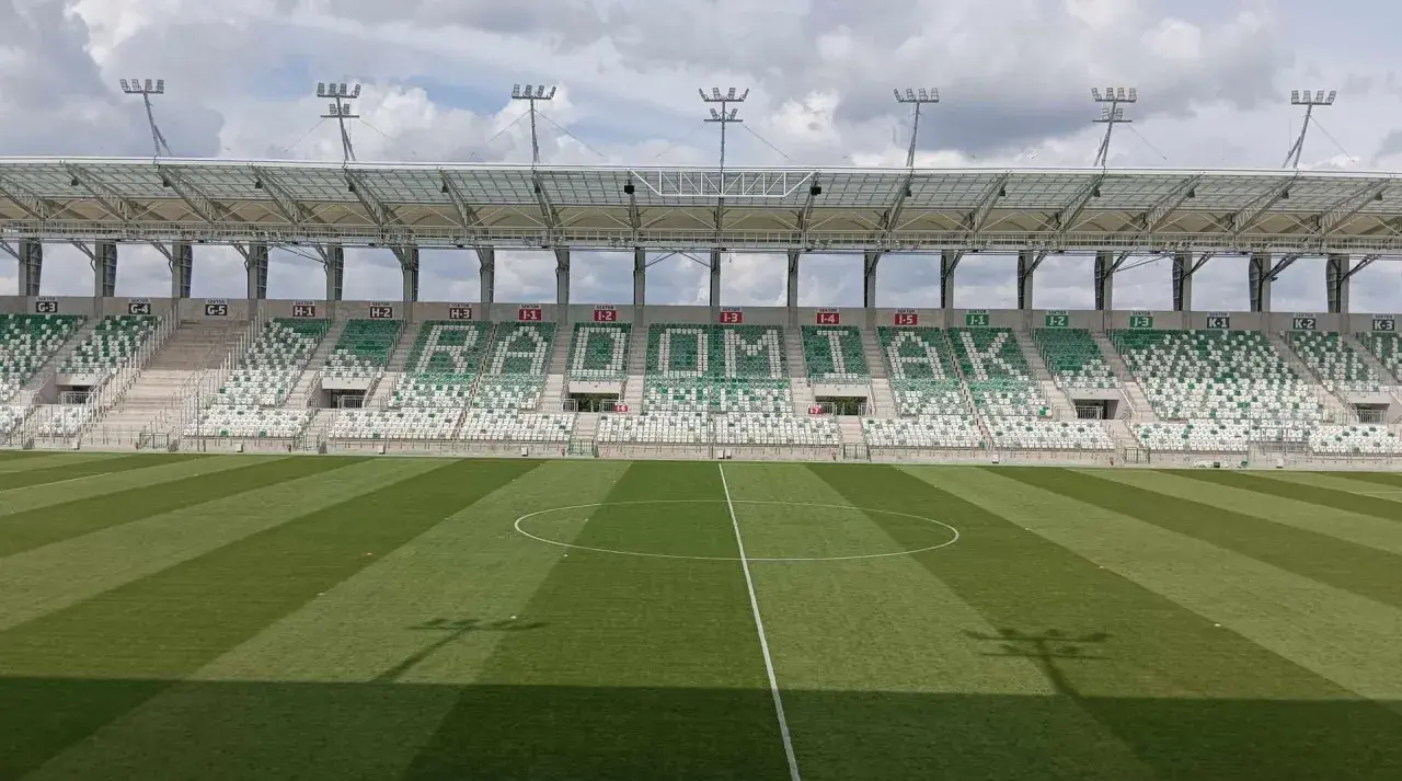 Puste trybuny stadionu RKS Radomiak Radom z napisem "RADOMIAK" ułożonym z zielonych i białych siedzeń.