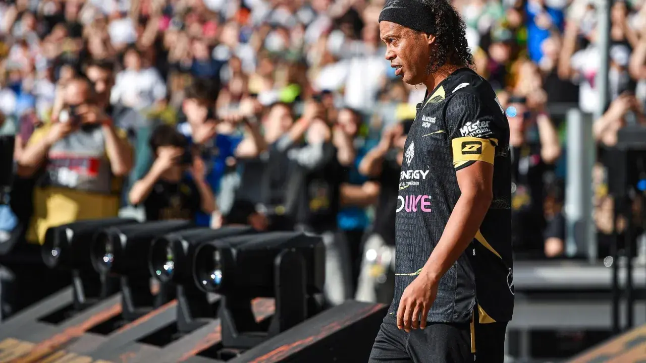 Ronaldinho w czarnej koszulce z żółtym opaską na ramieniu, z tłumem w tle.