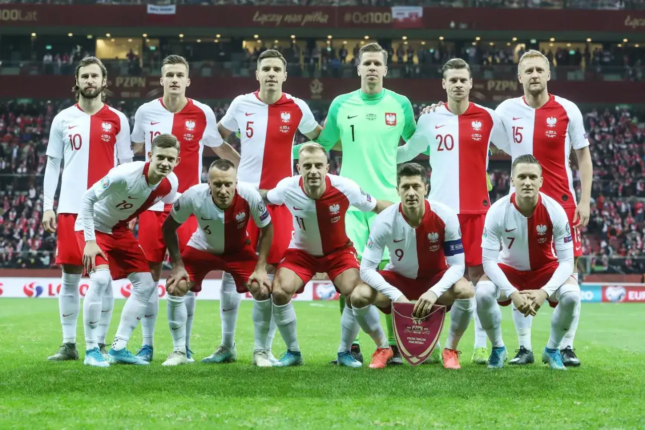 Drużyna narodowa Polski w piłce nożnej, gotowa do meczu z Słowenią. Piłkarze w biało-czerwonych strojach, z orłem na piersi.