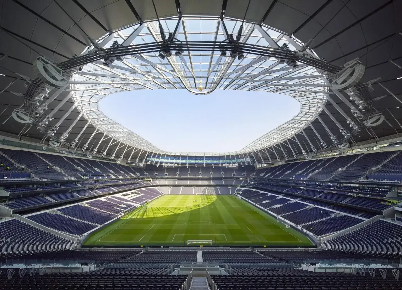 Nowoczesny stadion piłkarski z zieloną murawą i niebieskimi trybunami. Idealne miejsce, gdzie euro 2028 mogłoby dostarczyć niezapomnianych emocji.