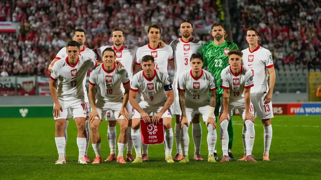 Drużyna Polski w piłce nożnej, gotowa do gry w barażach 2. ligi. Piłkarze w białych strojach z orłem na piersiach.