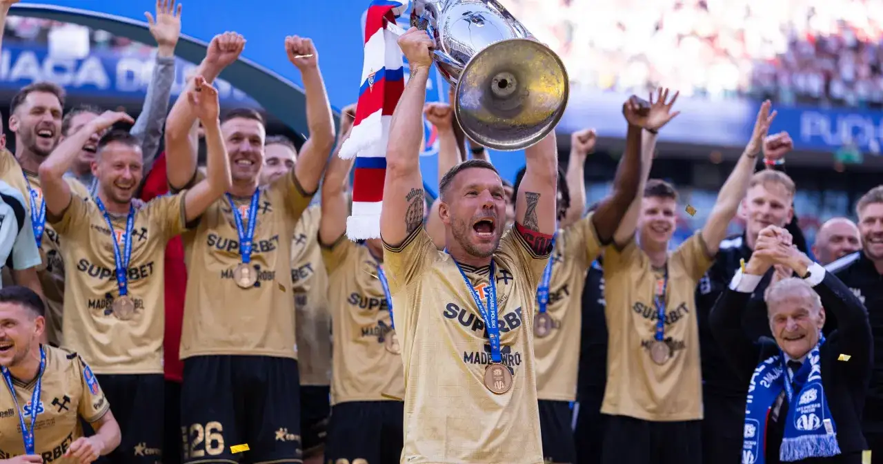Drużyna świętuje zdobycie Pucharu Polski. Piłkarze w złotych koszulkach z medalami na szyjach unoszą trofeum. Mistrz Polski w euforii!