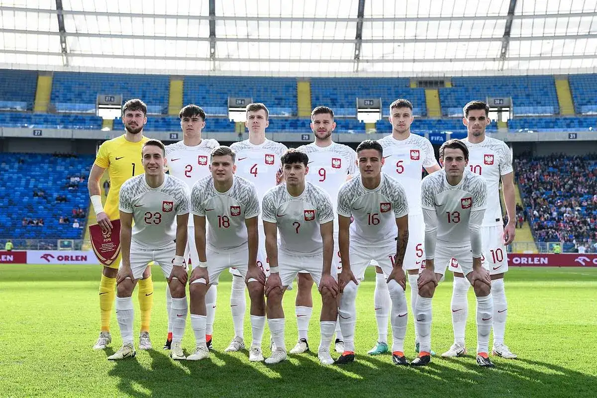 Młodzieżowa reprezentacja Polski w komplecie, gotowa do meczu na stadionie.
