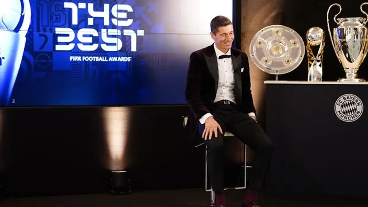 Robert Lewandowski, piłkarz roku FIFA, siedzi obok trofeów.