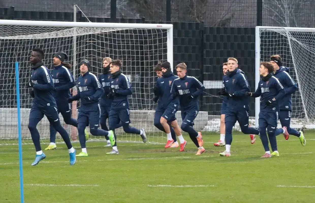 Piłkarze Pogoni Szczecin dzisiaj na treningu. Drużyna w granatowych strojach biega przy bramce.