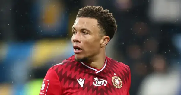 Piłkarz Rakowa Częstochowa w czerwonej koszulce z logo Lotto, gotowy do gry przeciwko Widzewowi Łódź.