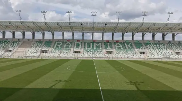 Puste trybuny stadionu RKS Radomiak Radom z napisem "RADOMIAK" ułożonym z zielonych i białych siedzeń.