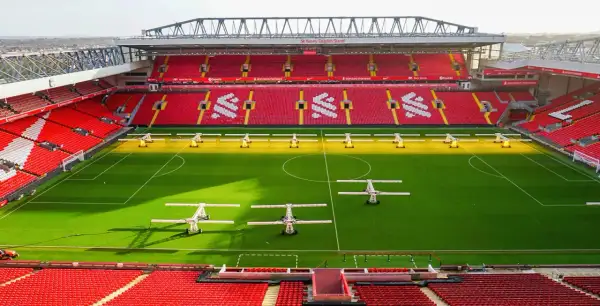 Piękny stadion w Anglii, Anfield, z czerwonymi trybunami i zieloną murawą, gotowy na kolejne emocjonujące mecze.