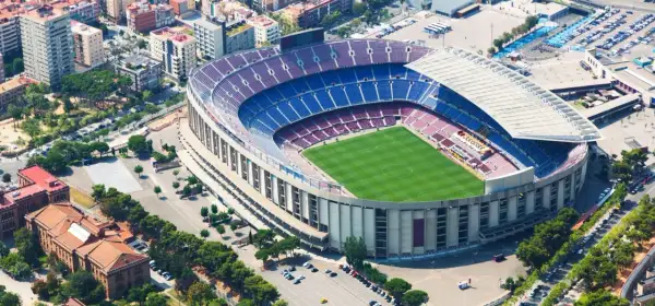 Widok z lotu ptaka na stadion Barcelony, z zieloną murawą i niebiesko-bordowymi trybunami.