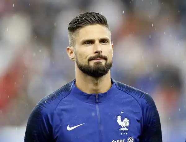 Olivier Giroud w deszczu, z charakterystycznymi fryzurami piłkarskimi i zarostem.
