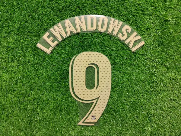 Numer 9 z nazwiskiem Lewandowski i logo Barcy na zielonej murawie.
