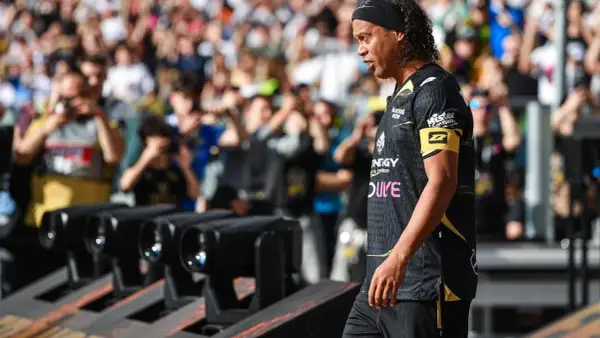 Ronaldinho w czarnej koszulce z żółtym opaską na ramieniu, z tłumem w tle.